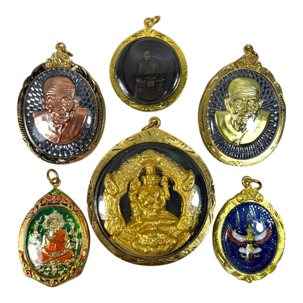 A Lot of 6 Vintage Gilt Thai Buddhist Amulets with Enamel Accents, 43AA: Comprising six pendants of varying shapes and sizes, ranging from 4.5 to 7 cm in height. Each amulet is encased in ornate gilt metal frames, several accented with colorful enamelwork. The group includ