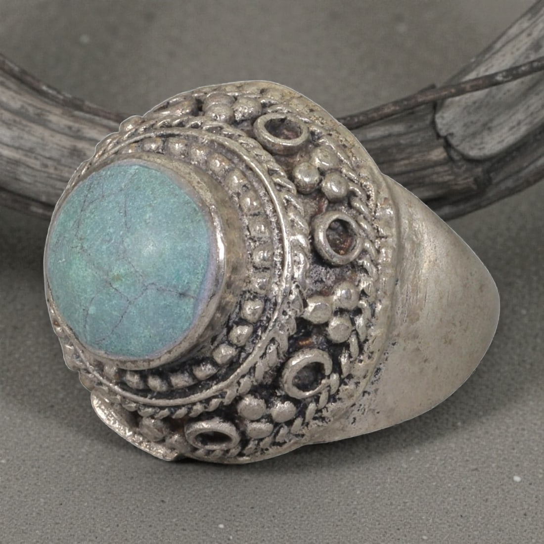A Middle Eastern Silver Plated Turquoise Ring, Late 19th-Early 20th Century, 11AK: The ring is centered with a round cabochon turquoise stone exhibiting natural light blue-green tones and surface veining, set within a domed bezel decorated with beaded granulation, twisted wirework, 