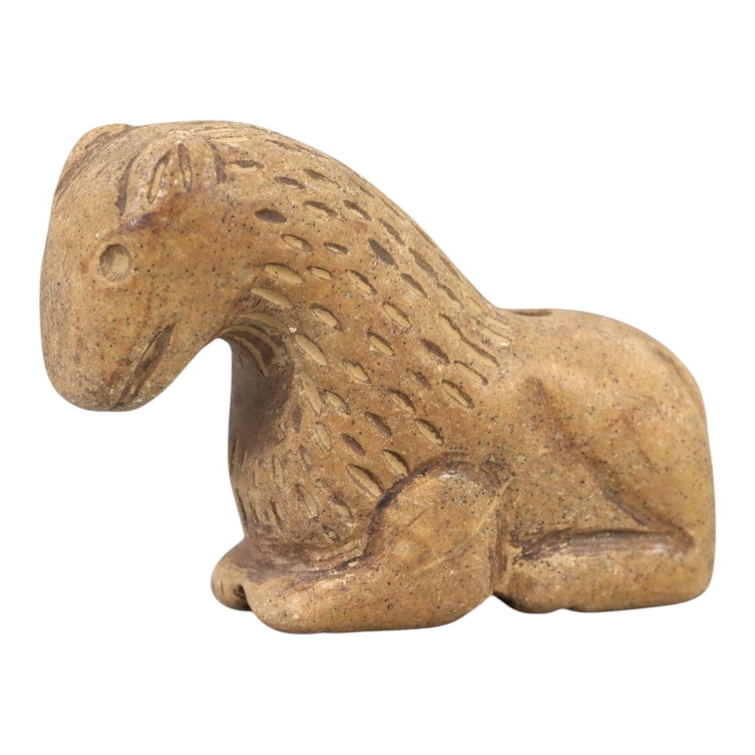 Ancient Stone Animal Amulet - Near Eastern Figurine, 86AL: Carved from tan speckled stone, this amulet depicts a recumbent quadrupedal animal, likely a canine or feline, with incised linear patterns across its body to denote fur. The head is rounded with a si