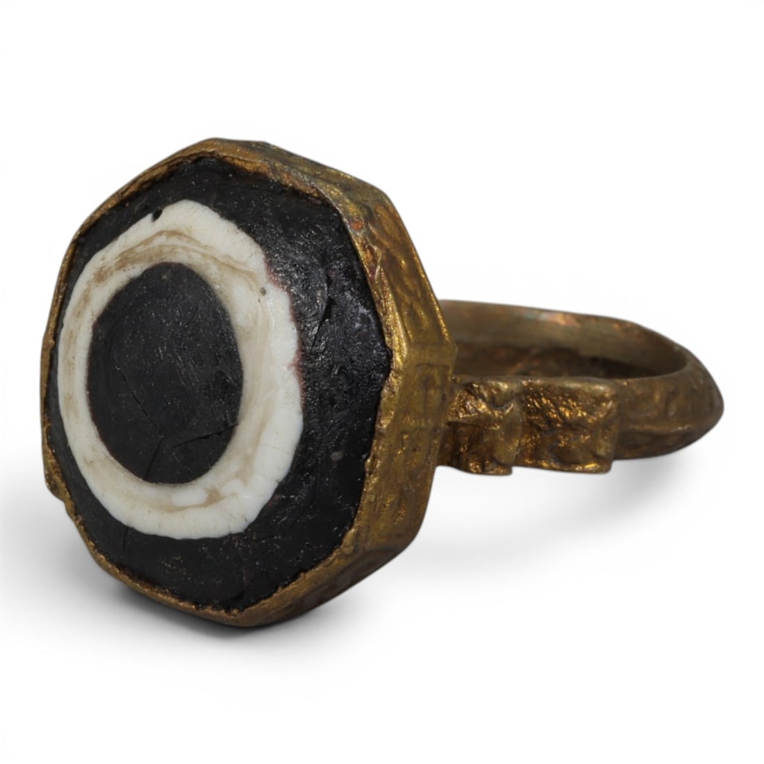 Antique Qajar Dynasty Gilt Evil Eye Ring, US Size 9.5, 16AJ: A gilt-metal ring of the Qajar period, US ring size 9.5, featuring an octagonal evil-eye glass inlay with a bold concentric black-and-white design (the glass exhibits age-related cracks). The bezel is