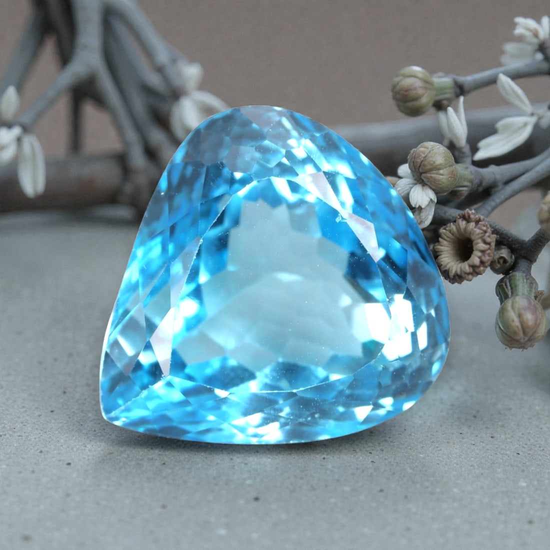 42.01 Carats Swiss Blue Topaz Trillion - Natural Brazilian Stone, LZ106: This bold trillion-cut Swiss blue topaz commands attention with its vivid, saturated sky-blue hue and crisp geometric silhouette. The expertly faceted cut features precisely angled surfaces that captu