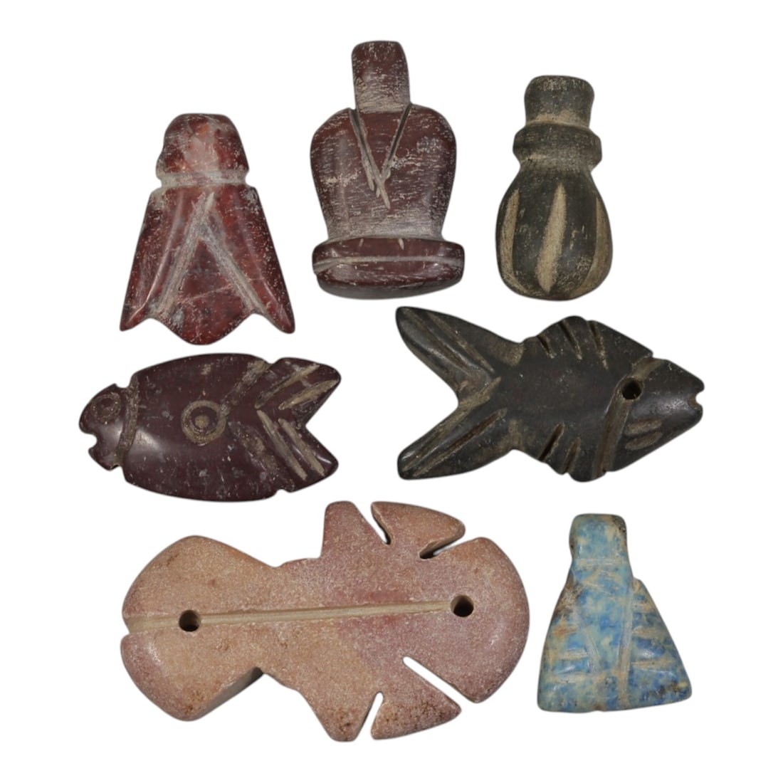 Lot of 7 Ancient Coptic Egyptian Multi-Stone Amulets, Circa Roman to Coptic Era, 87AH: Carved from various earth-toned stones including reddish-brown, dark grey, pinkish, and blue-speckled varieties, the group consists of seven distinct amulets, ranging in size from 2 cm to 4 cm (0.79-1
