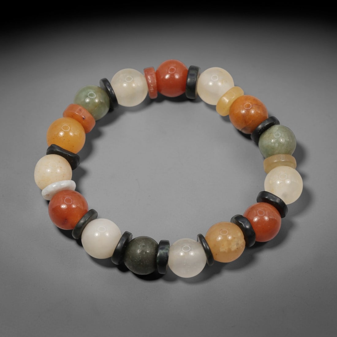 A Chinese Quartz and Jadeite Jade Bead Bracelet, 20th Century, 48ZK: Strung with spherical beads of quartz and jadeite jade, separated by flat disc-shaped spacers. The quartz beads display natural color variation, including white, yellow, orange, and reddish-orange, wi