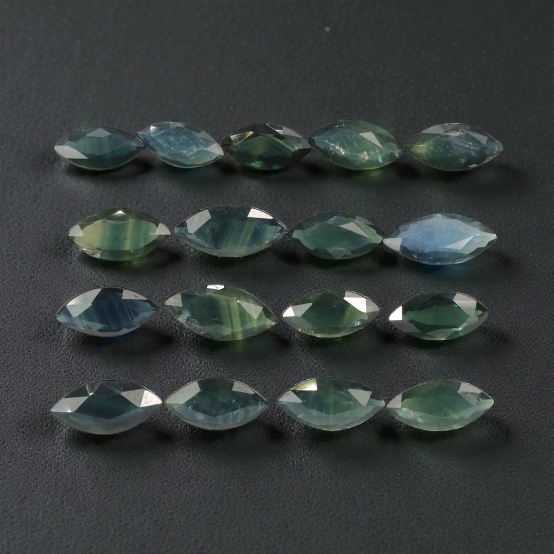 10.14 Carats Natural Teal Green Australian Sapphire Parcel - 17pcs Heated Only, 21YE: This extensive parcel of 17 marquise-cut sapphires presents a stunning range of cool teal and green hues, from soft aquamarine to deep forest green, with subtle color banding visible in many stones. T