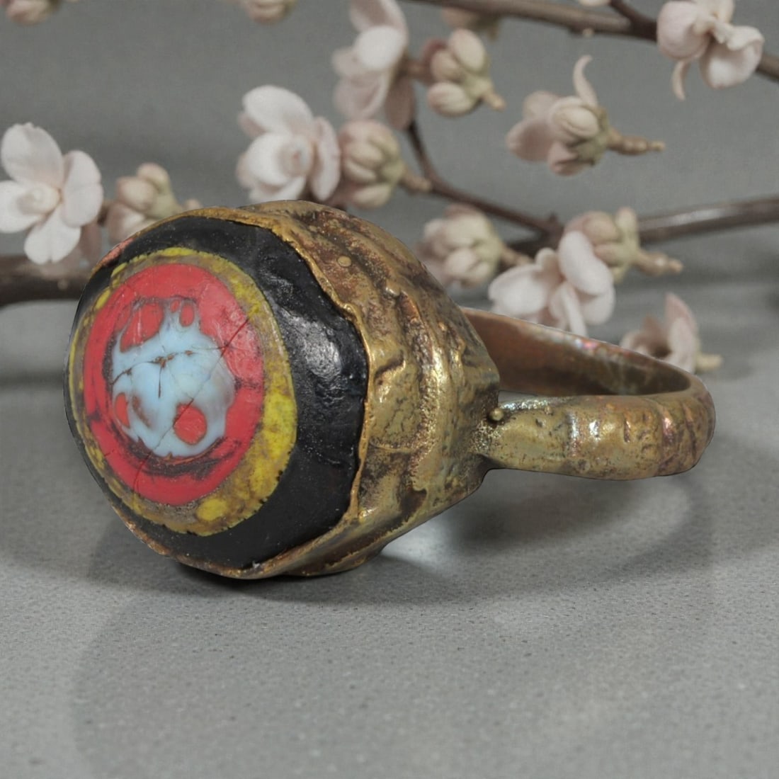 Antique Qajar Dynasty Gilt Evil Eye Ring, US Size 9.5, 11AJ: A gilt-metal ring of the Qajar period, US ring size 9.5, featuring a large, domed evil-eye glass inlay with vibrant concentric red, yellow, black, and white layers. The central motif is a stylized evi