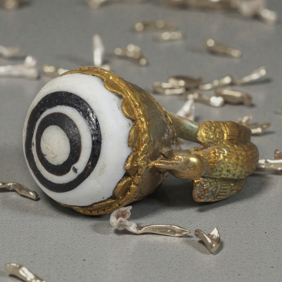 Antique Qajar Dynasty Gilt Evil Eye Ring, US Size 8.5, 6AJ: A gilt-metal ring of the Qajar period, US ring size 8.5, featuring a large domed evil-eye glass inlay with a bold concentric black-and-white design. The bezel is adorned with a decorative scalloped ed