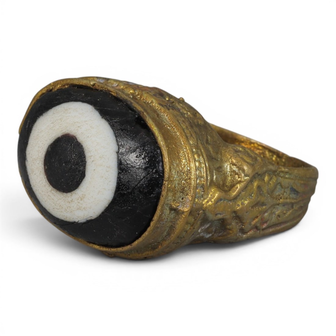 Antique Qajar Dynasty Gilt Evil Eye Ring, US Size 7.5, 36AJ: A gilt-metal ring of the Qajar period, US ring size 7.5, featuring a large domed evil-eye glass inlay with a bold concentric black-and-white design (the glass exhibits age-related cracks and patina). 