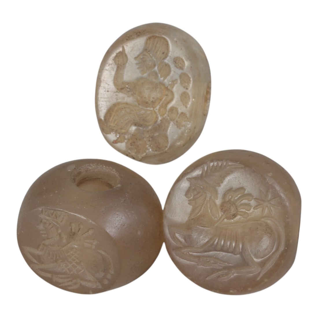 Lot of 3 Ancient Sasanian Chalcedony Stamp Seals, Circa 3rd-7th Century CE, 70WP: A collection of three Sasanian period stamp seals, expertly carved from translucent chalcedony stone, each featuring a central drilled hole for suspension. The seals display characteristic Sasanian ic