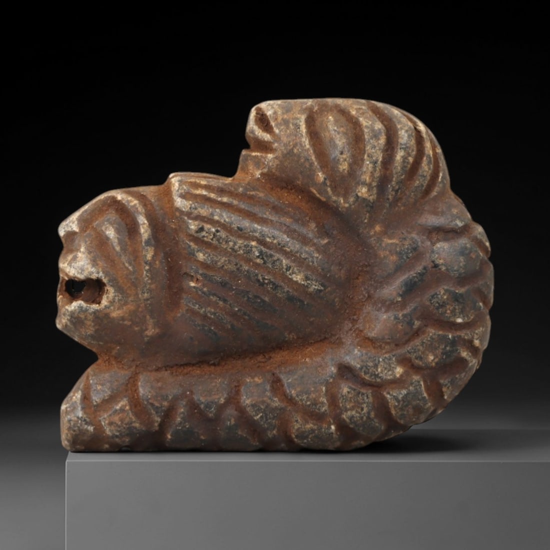 Ancient Steatite Lion - Near Eastern Amulet Figurine, 97AK: Carved from steatite, this amulet depicts a recumbent lion with incised linear details defining the mane, facial features, and body, including a suspension hole in the muzzle for wearable use. Attribu