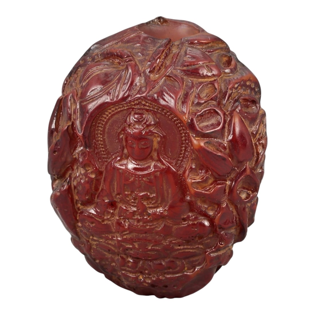 A Buddhist Amber-Resin Bead, 20th Century, 79FC: Molded from translucent reddish-brown amber-colored resin with lighter inclusions and surface variation, the object is formed as a bead carved in relief with Buddhist imagery. One face depicts a seate