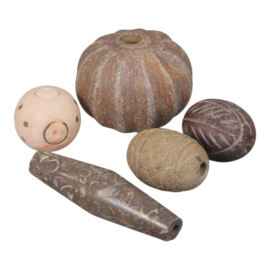 Lot of 5 Ancient Near Eastern Stone Beads, 1st Millennium BCE, 28AE: Comprising five beads of varying form and material. One spherical bead of light pink stone with incised circular and dot motifs. One large ribbed gourd-shaped bead of brown stone. One ovoid bead of br
