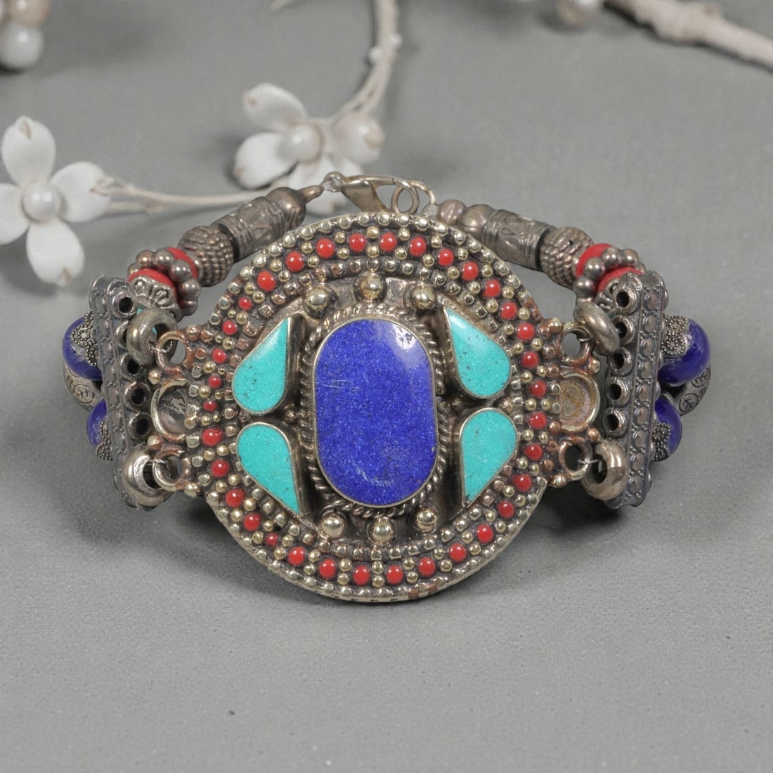 A Vintage Himalayan Silver-Plated Multi-Stone Inlay Bracelet, 5AH: A handcrafted vintage bracelet, measuring approximately 7 cm in width, showcasing traditional Himalayan jewelry design. The piece features a silver-plated metal base with a large central oval lapis la