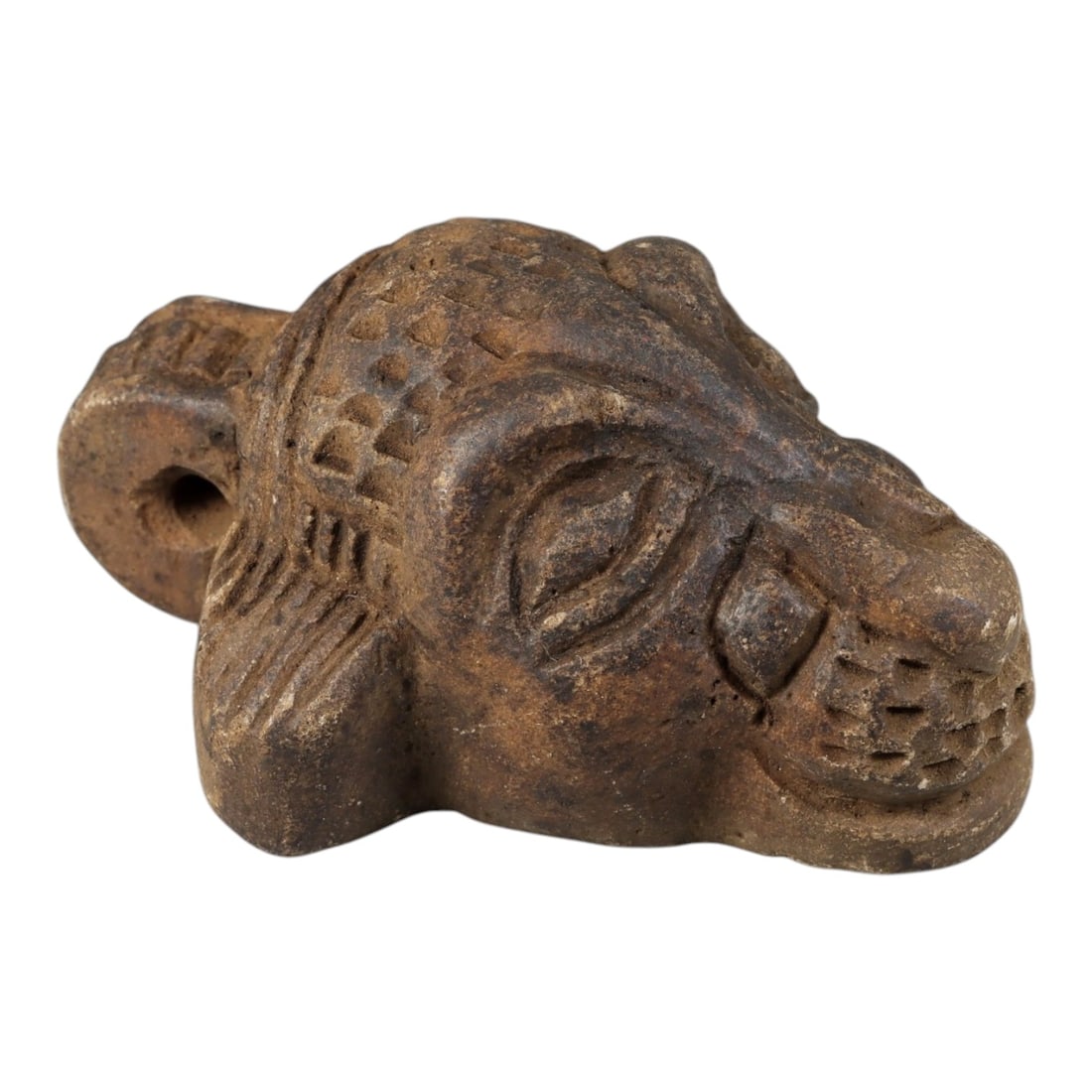 Ancient Stone Zoomorphic Amulet - Near Eastern Animal Head, 74BD: Carved from a dense, dark stone, this artifact takes the form of a stylized zoomorphic animal head, rendered with detailed incised decoration. The head features large, recessed almond-shaped eyes, a b