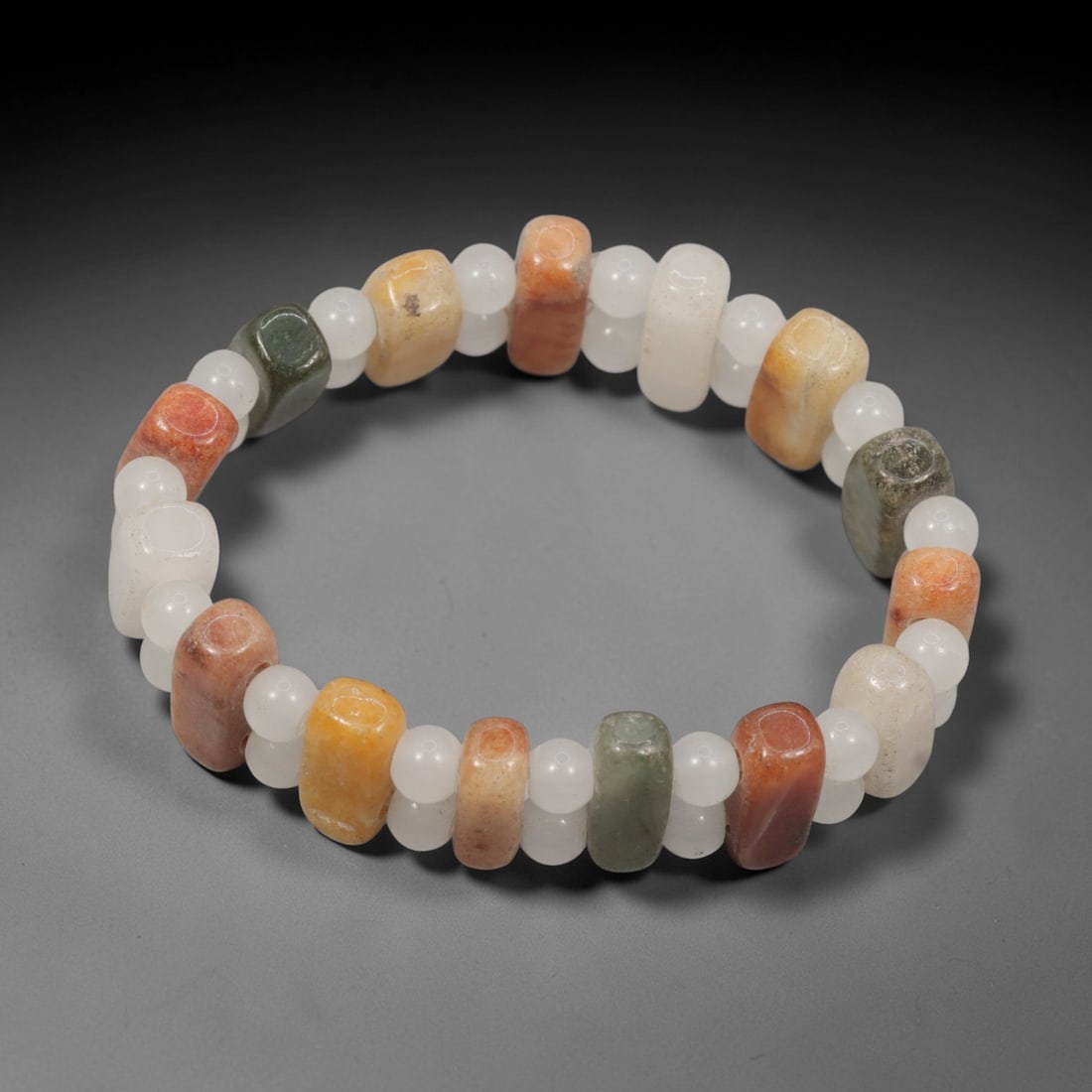 A Chinese Quartz and Jadeite Jade Bead Bracelet, 20th Century, 32ZK: Strung with barrel-shaped beads of quartz and jadeite jade, alternating with small spherical white quartz spacer beads. The quartz barrel beads exhibit natural color variations including white, pale y