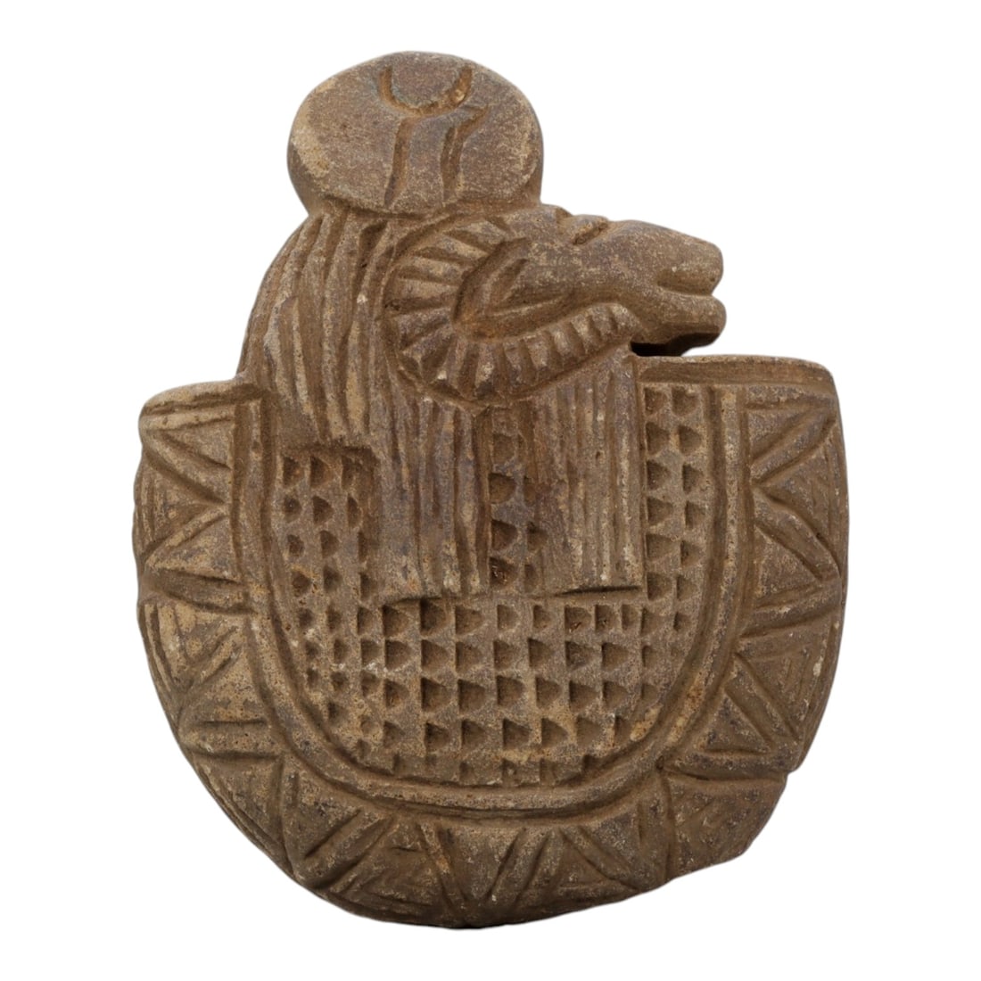 Ancient Stone Plaque - Near Eastern Ram-Headed Figure, 19WS: Carved from a compact, earth-toned stone, the plaque depicts a ram-headed deity or protective figure set within a shield-shaped frame. The figure is adorned with a solar disk headdress and a stylized 
