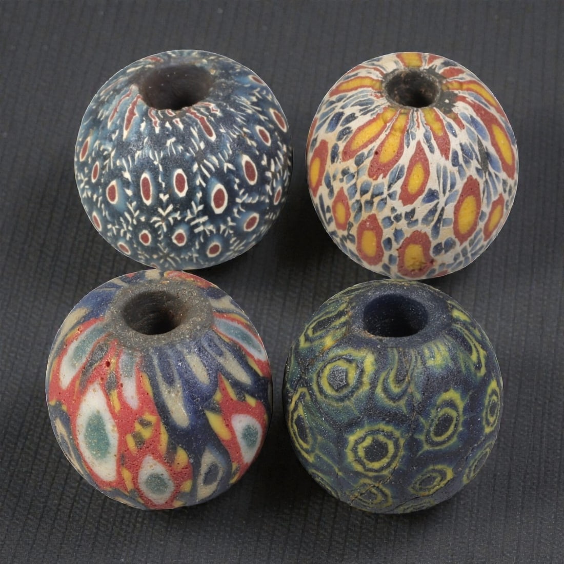 Lot of 4 Ancient to Antique Polychrome Glass Beads, 1st Mil BCE to Islamic Period, 34WM: A group of four spherical polychrome glass beads, each with a central perforation. The beads feature intricate mosaic and millefiori-style decoration, including eye motifs, feather patterns, and compo