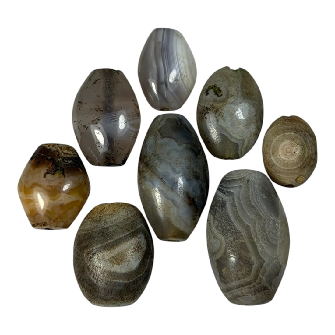 A Lot of 9 Himalayan Banded Agate Beads, Ancient to Antique Period, 39AN: Comprising lot of barrel and ovoid beads, each carved from banded agate with natural tonal variations, many displaying characteristic concentric, linear, and dendritic patterns. The surfaces exhibit s