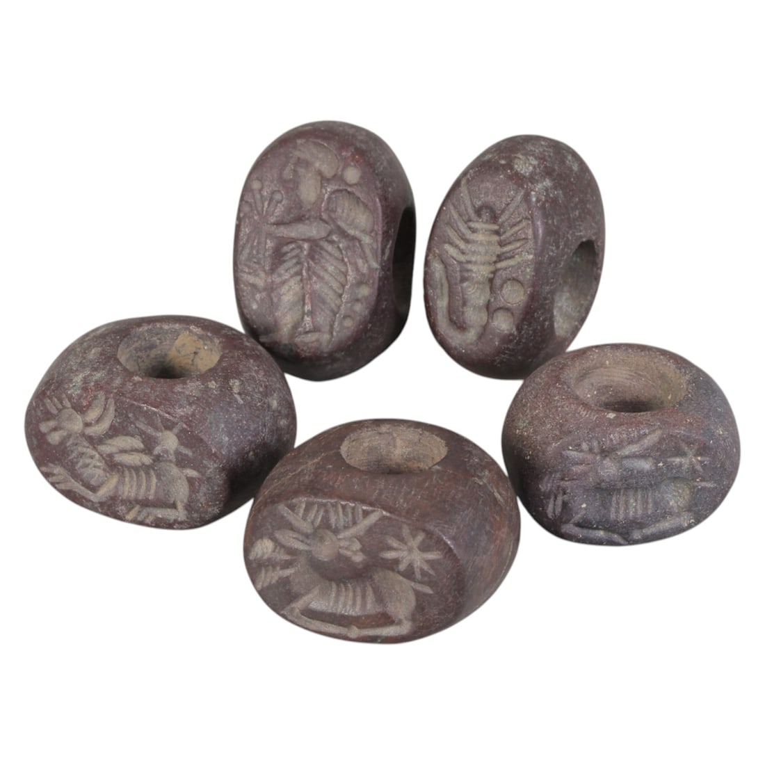 Lot of 5 Sasanian Stone Stamp Seals, Circa 3rd-7th Century CE, 98AE: Comprising five seals carved from dark reddish-brown stone with natural patina and surface wear consistent with ancient use. Each seal is of flattened disc to oval form with a central perforation for 