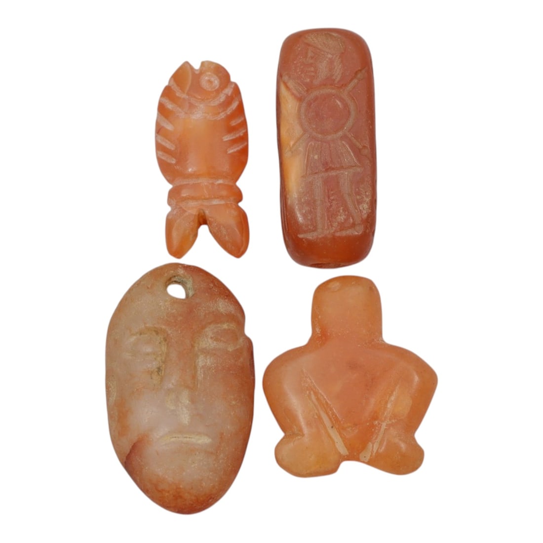 Lot of 4 Coptic Egyptian Carnelian Amulets, Circa Roman to Coptic Era, 18WS: The group comprises four carnelian amulets, each carved from orange-red stone with natural translucency and surface patina. The forms include a stylized fish, a rectangular seal bead incised with a st