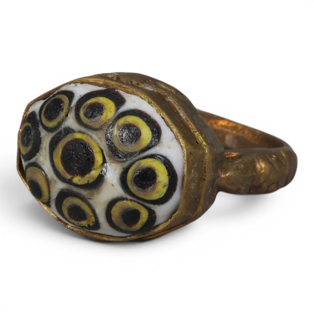 Antique Qajar Dynasty Gilt Evil Eye Ring, US Size 9, 44AJ: A gilt-metal ring of the Qajar period, US ring size 9, featuring a large oval glass inlay decorated with a striking multi-eye motif. The white glass base is adorned with multiple concentric evil-eye p