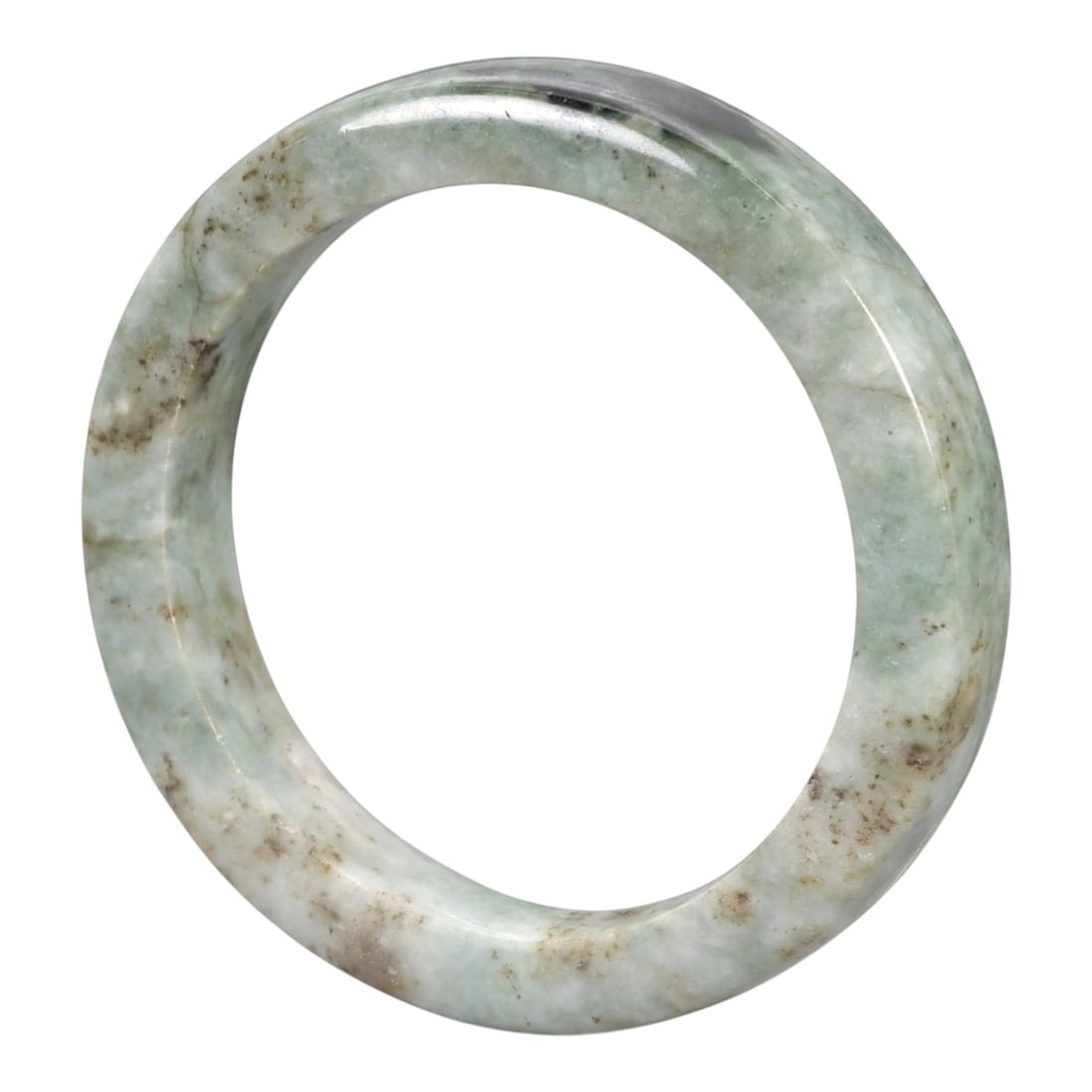 A Chinese Jadeite Jade Bangle Bracelet, 20th Century, 87ZK: Carved from jadeite jade with a pale green base and scattered brownish inclusions, the bangle is formed as a continuous circular band with a rounded cross-section. The surface is smoothly polished, wi