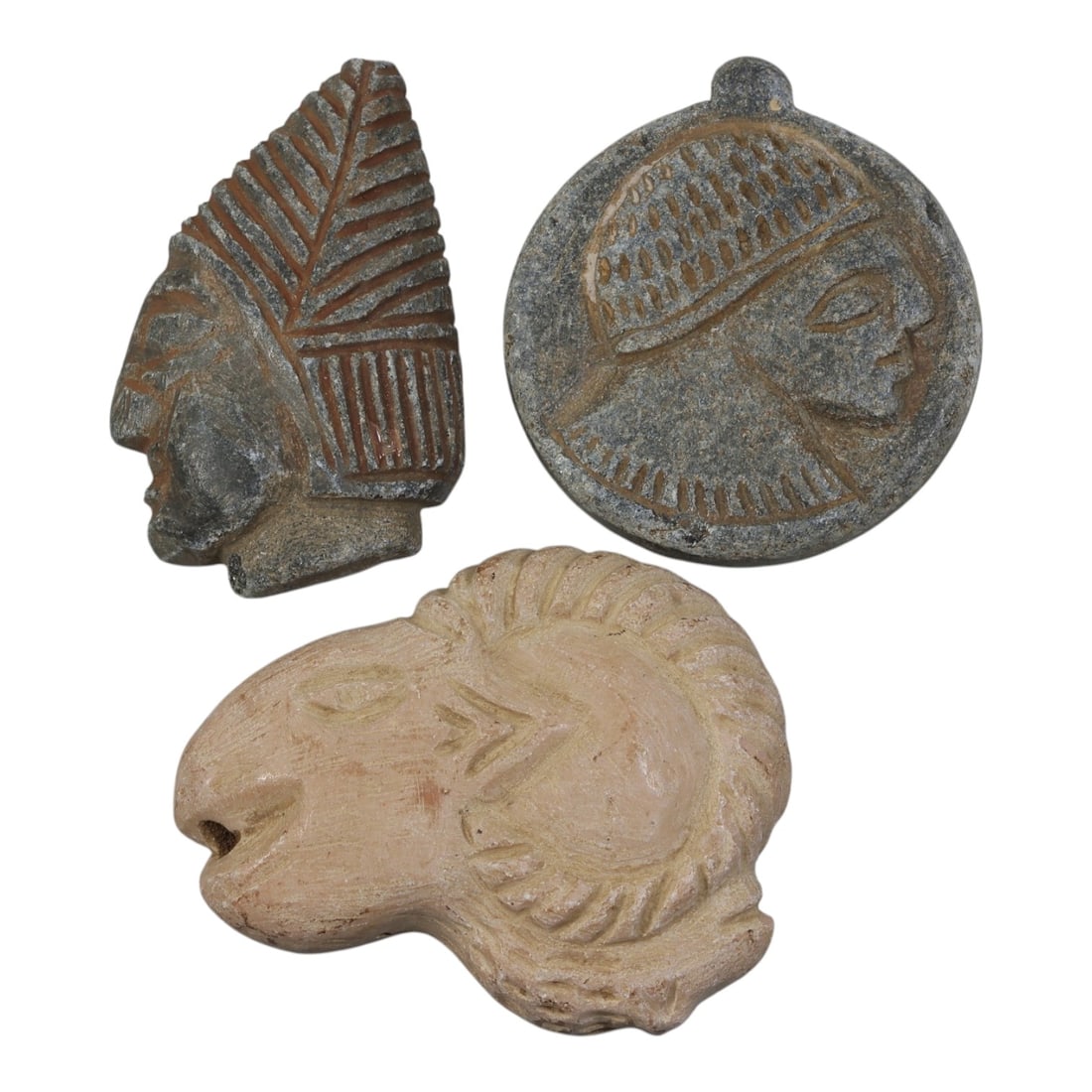 Lot of 3 Ancient Near Eastern Stone Carvings, Circa 1st Millennium BCE, 32AE: Comprising three carved stone objects of varying form and material. One grey stone head fragment carved in profile, wearing a tall headdress with incised linear details. One circular grey stone pendan