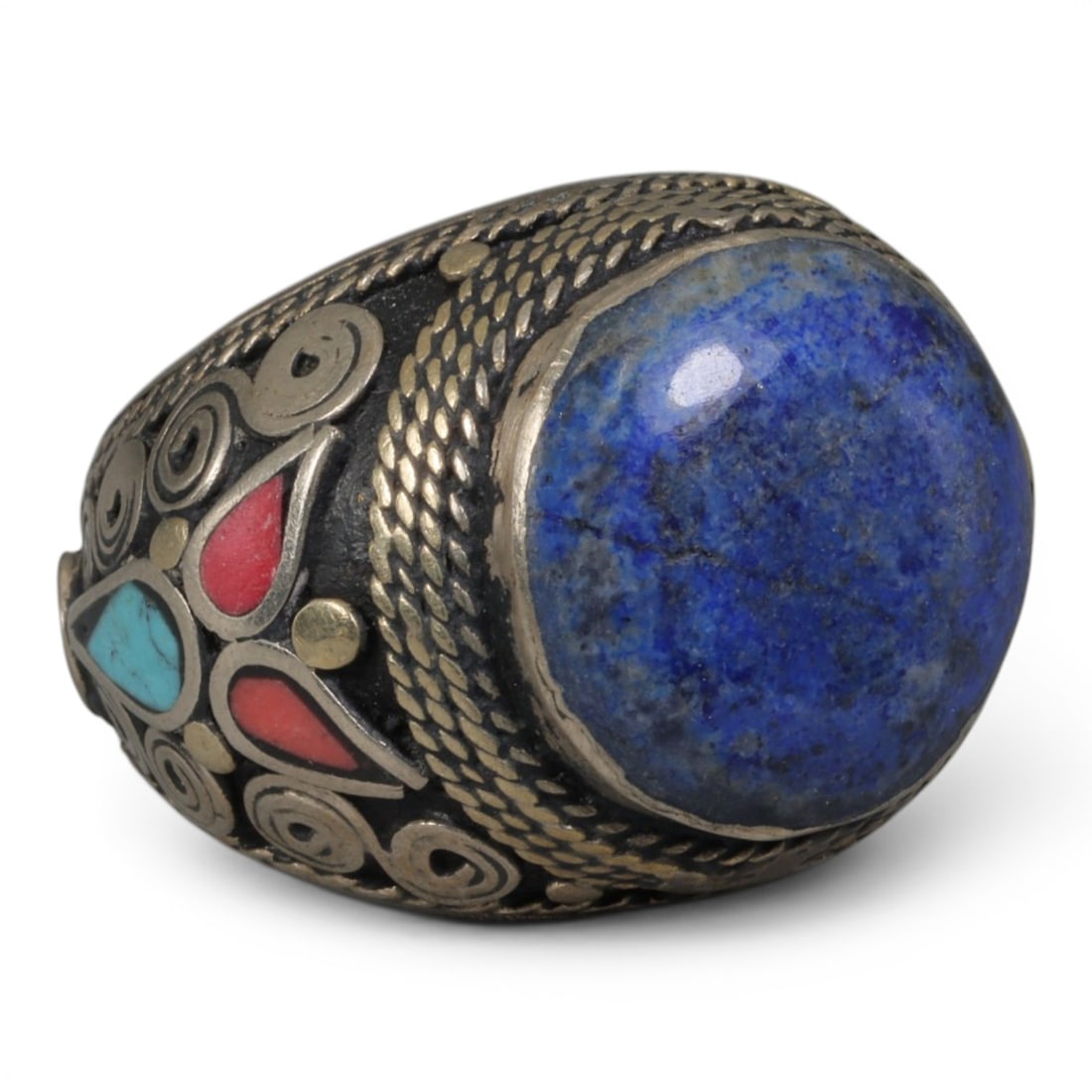 Antique Central Asian Silver and Lapis Lazuli Tribal Ring, 19th-Early 20th Century, 34AJ: The ring is set with a large, smooth cabochon lapis lazuli stone, displaying natural pyrite inclusions and surface cracks within its deep blue matrix. The silver mount is decorated with pseudo-filigre