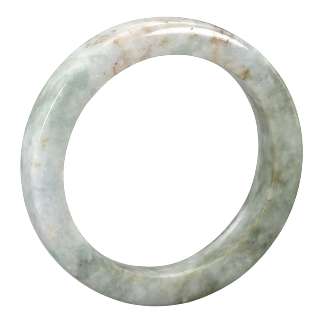 A Chinese Jadeite Jade Bangle Bracelet, 20th Century, 85ZK: Carved from jadeite jade with a pale greenish-white base and scattered light brownish inclusions, the bangle is formed as a continuous circular band with a rounded cross-section. The surface is smooth