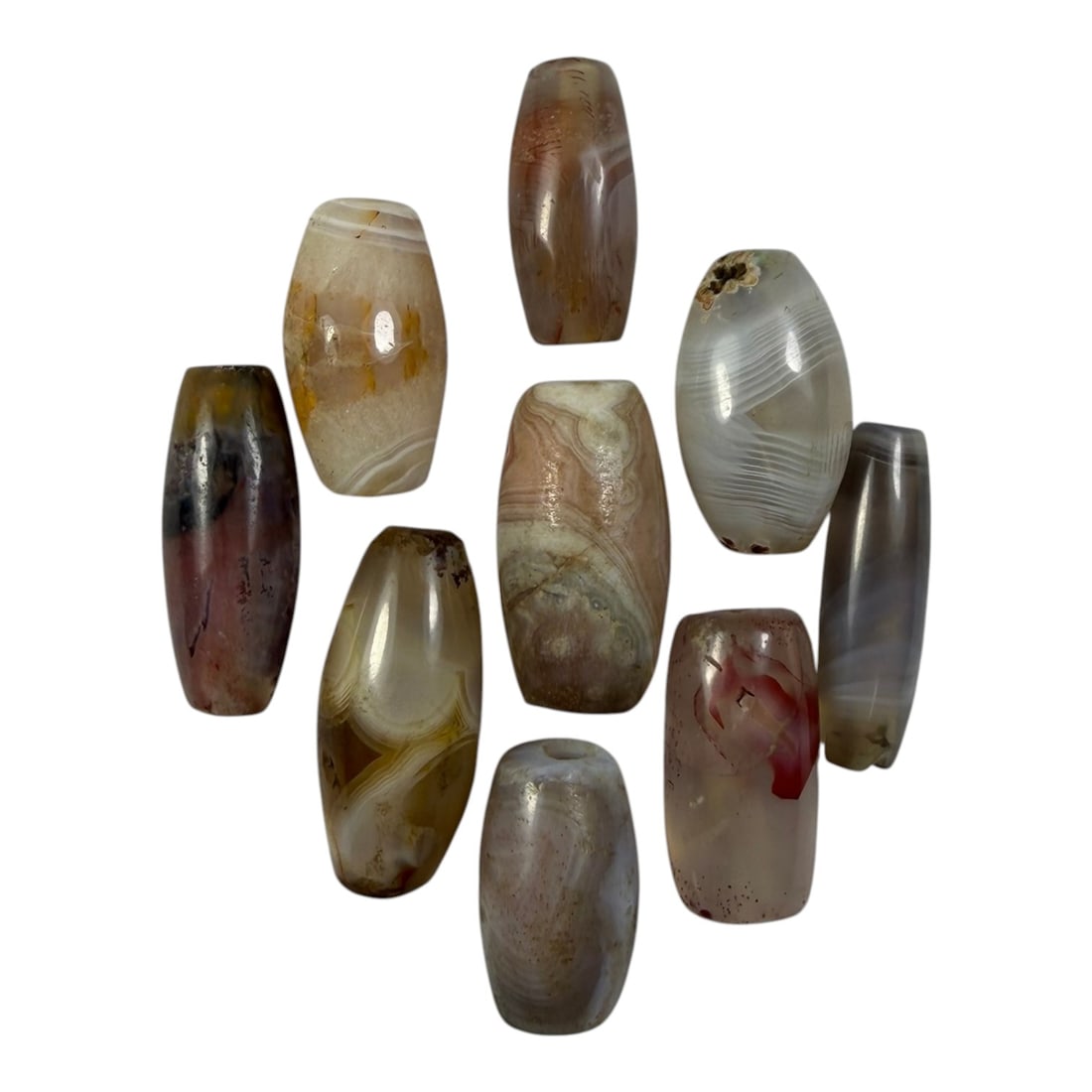 A Lot of 9 Himalayan Banded Agate Beads, Ancient to Antique Period, 19YD: Comprising lot of barrel and ovoid beads, each carved from banded agate with natural tonal variations, many displaying characteristic concentric, linear, and dendritic patterns. The surfaces exhibit s