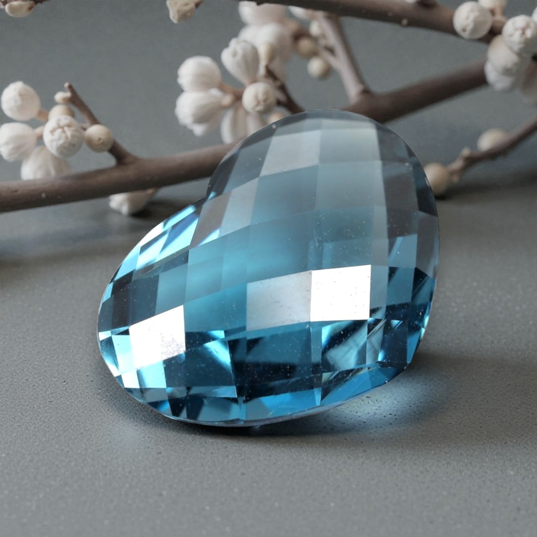 14.61 Carats London Blue Topaz Heart - Natural Loose Gemstone, LZ61: This stunning 14.61 carat London Blue Topaz is precision-cut into a romantic heart shape, measuring 19.4mm x 13.7mm x 7.1mm. It exhibits a rich, deep ocean-blue hue with subtle grey undertones, charac