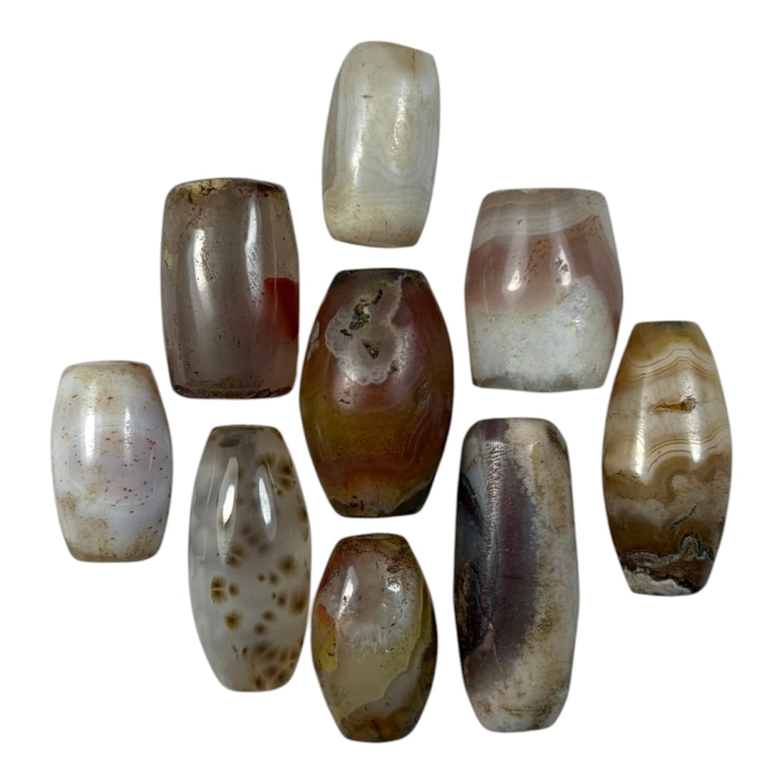 A Lot of 9 Himalayan Banded Agate Beads, Ancient to Antique Period, 21YD: Comprising lot of barrel and ovoid beads, each carved from banded agate with natural tonal variations, many displaying characteristic concentric, linear, and dendritic patterns. The surfaces exhibit s