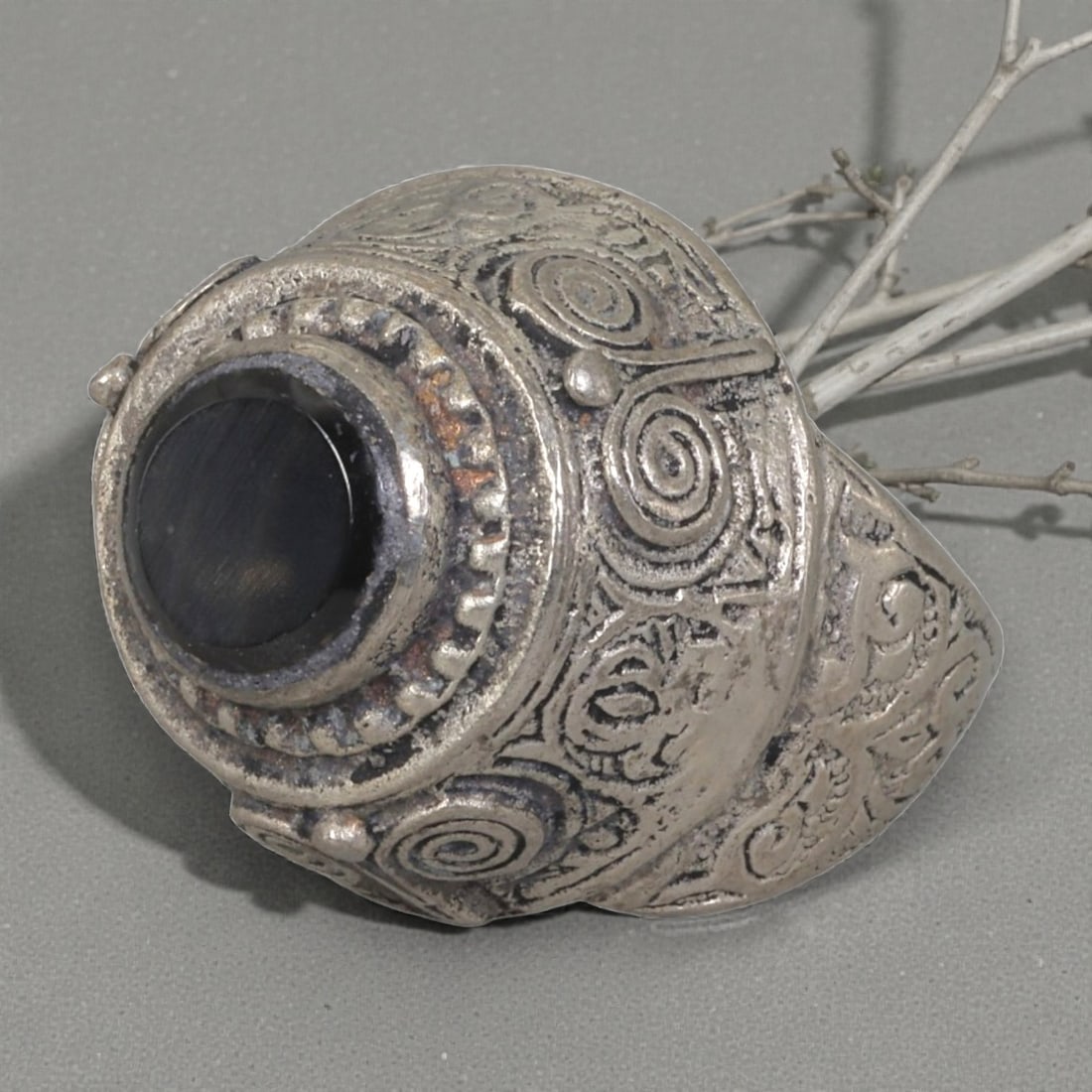 A Middle Eastern Silver Plated Onyx Ring, Late 19th-Early 20th Century, 9AK: The ring is centered with a round cabochon onyx stone set within a domed bezel featuring a raised beaded border. The bezel and shoulders are engraved with stylized spiral and foliate motifs. The silve