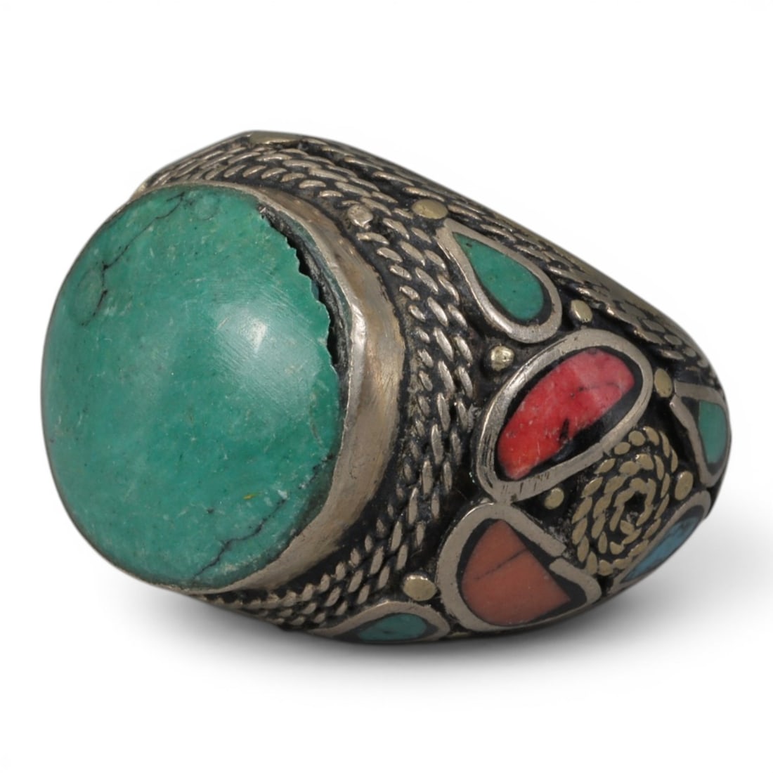 Antique Central Asian Silver and Turquoise Tribal Ring, 19th-Early 20th Century, 70AJ: The ring is set with a large cabochon turquoise stone, displaying natural matrix inclusions and surface cracks within its green-blue matrix. The silver mount is decorated with pseudo-filigree scale-pa