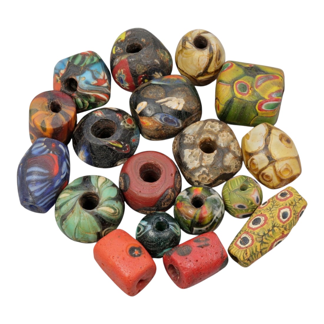 A Lot of 18 Antique/ Vintage Artisan Glass Trade Beads, 29WM: A diverse collection of 18 glass trade beads, varying in form from spherical, barrel, and cylindrical to polygonal and faceted shapes, all with central perforations. The beads showcase intricate mosai