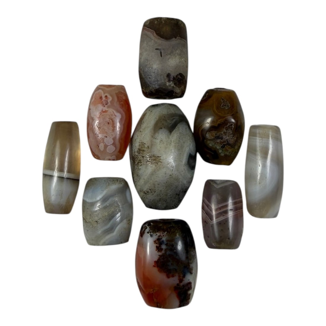 A Lot of 9 Himalayan Banded Agate Beads, Ancient to Antique Period, 29YD: Comprising lot of barrel and ovoid beads, each carved from banded agate with natural tonal variations, many displaying characteristic concentric, linear, and dendritic patterns. The surfaces exhibit s