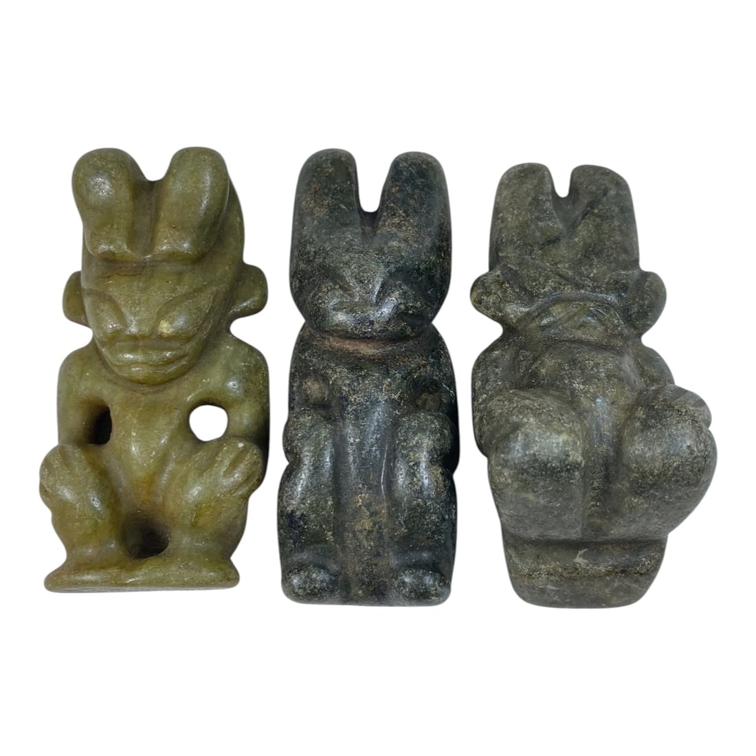 A Lot of 3 Chinese Hongshan-Style Jade Deity Figurines, 65AB: This collection features three Hongshan-style jade carvings depicting seated anthropomorphic deities, crafted from natural jade in varying tones of light green, dark green, and grey-green, exhibiting 