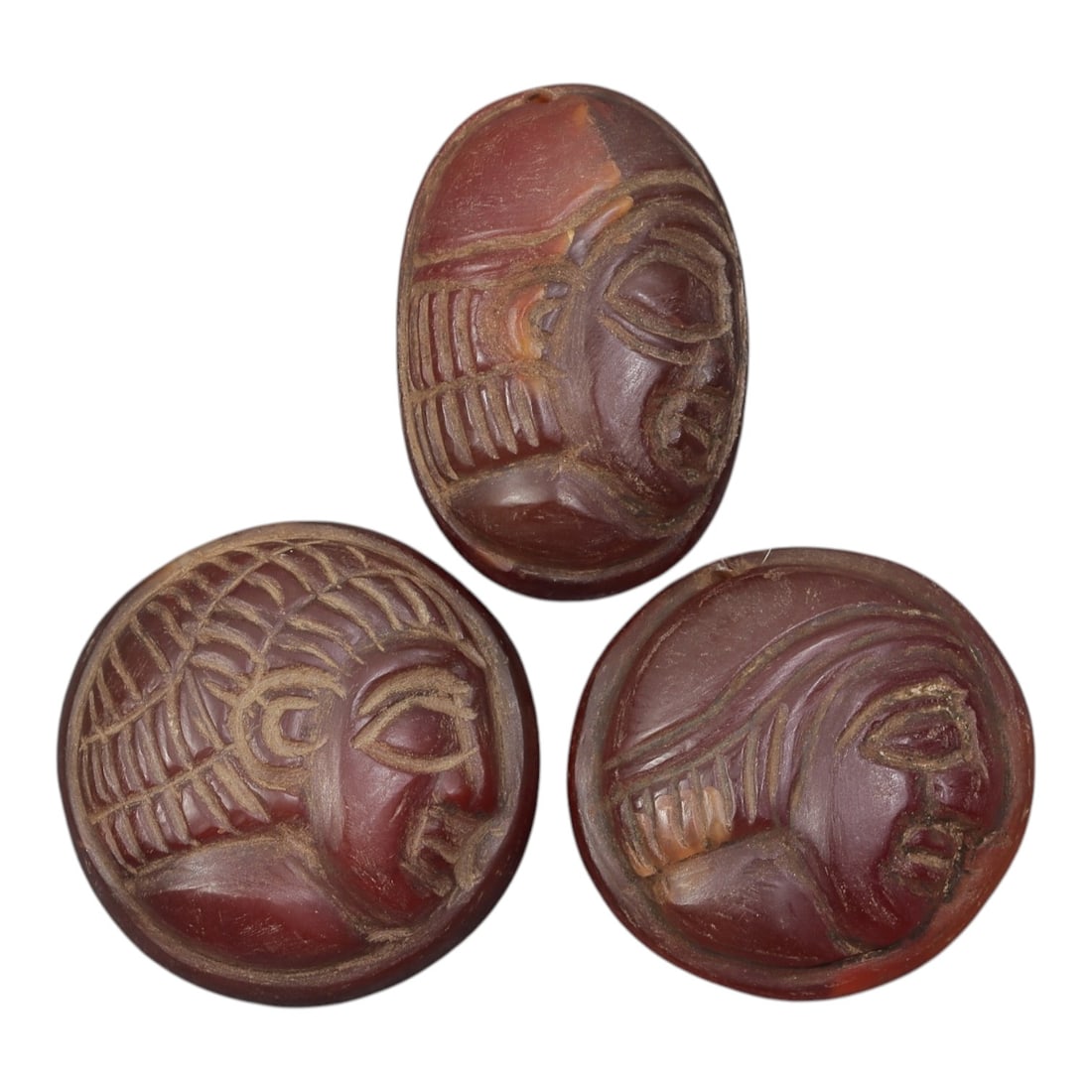 Lot of 3 Ancient Coptic Egyptian Carnelian Face Beads, Circa Roman to Coptic Era, 22AE: Comprising three finely carved carnelian beads ranging from 3 cm to 3.5 cm, these pieces are characteristic decorative and protective jewelry from the Coptic Egyptian period. Each bead is incised with