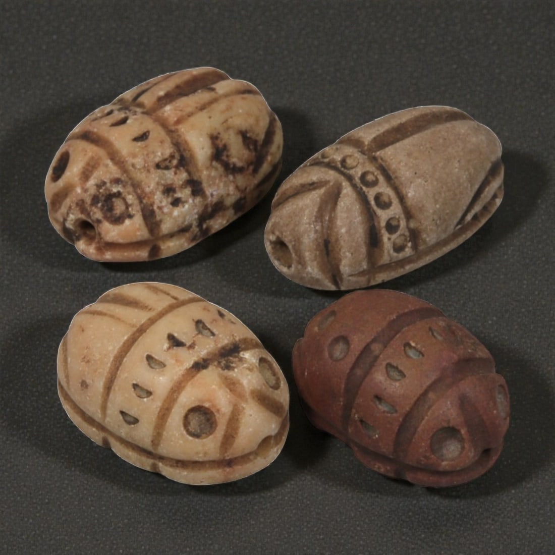 Lot of 4 Natural Coptic Egyptian Multi-Stone Scarab Amulets, Circa Roman to Coptic Era, 94WT: A group of four scarab amulets carved from various stones, including light beige and reddish-brown examples. Each is formed as a stylized scarab beetle with incised carapace details, including lines, 