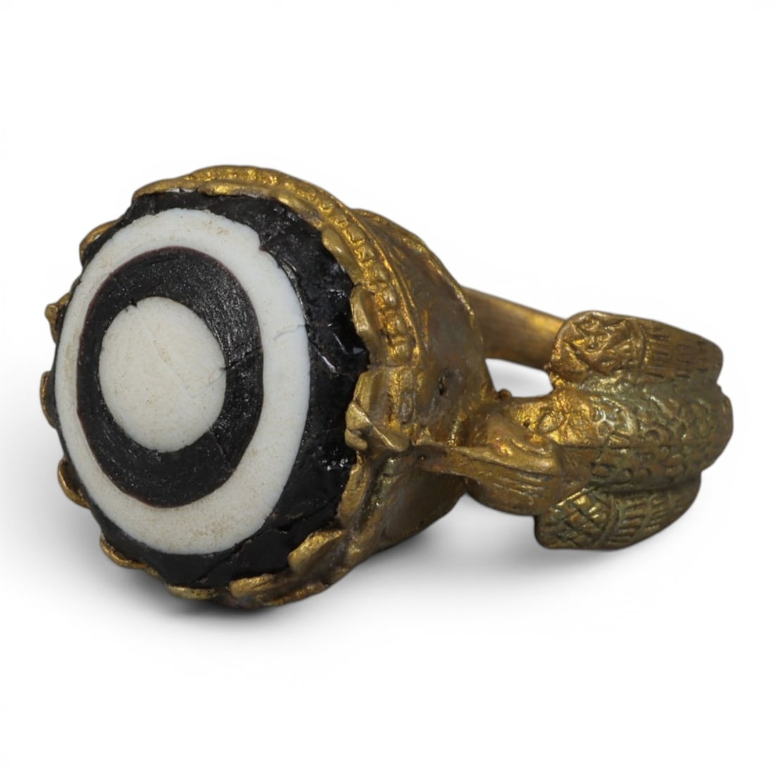 Antique Qajar Dynasty Gilt Evil Eye Ring, US Size 8.5, 22AJ: A gilt-metal ring of the Qajar period, US ring size 8.5, featuring a large domed evil-eye glass inlay with a bold concentric black-and-white design (the glass exhibits age-related cracks). The bezel i