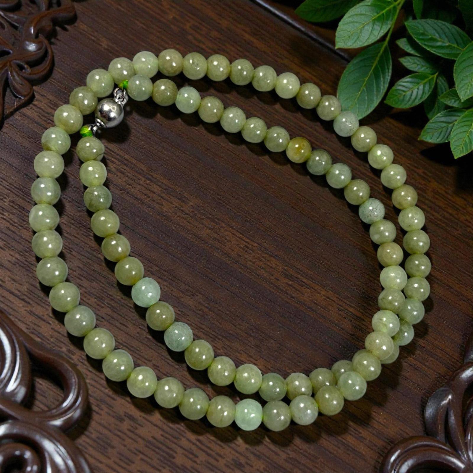 Chinese Jadeite Jade Bead Necklace, 20th Century, 89XC: A continuous strand of polished jadeite beads, each of uniform spherical form, displaying soft yellow-green and pale green tones with natural mineral inclusions and subtle variations in translucency. 