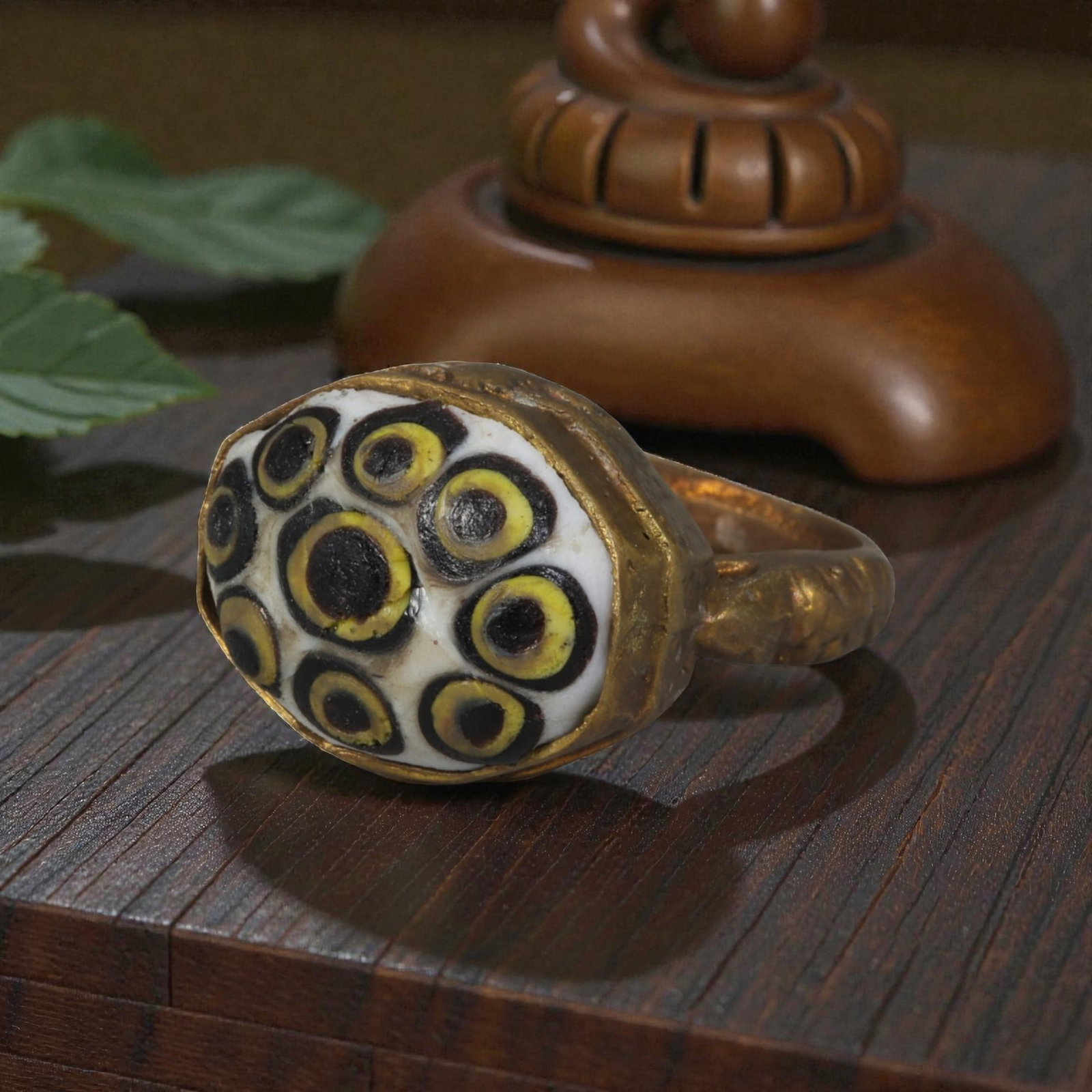 Antique Qajar Dynasty Gilt Evil Eye Ring, US Size 9, 44AJ: A gilt-metal ring of the Qajar period, US ring size 9, featuring a large oval glass inlay decorated with a striking multi-eye motif. The white glass base is adorned with multiple concentric evil-eye p