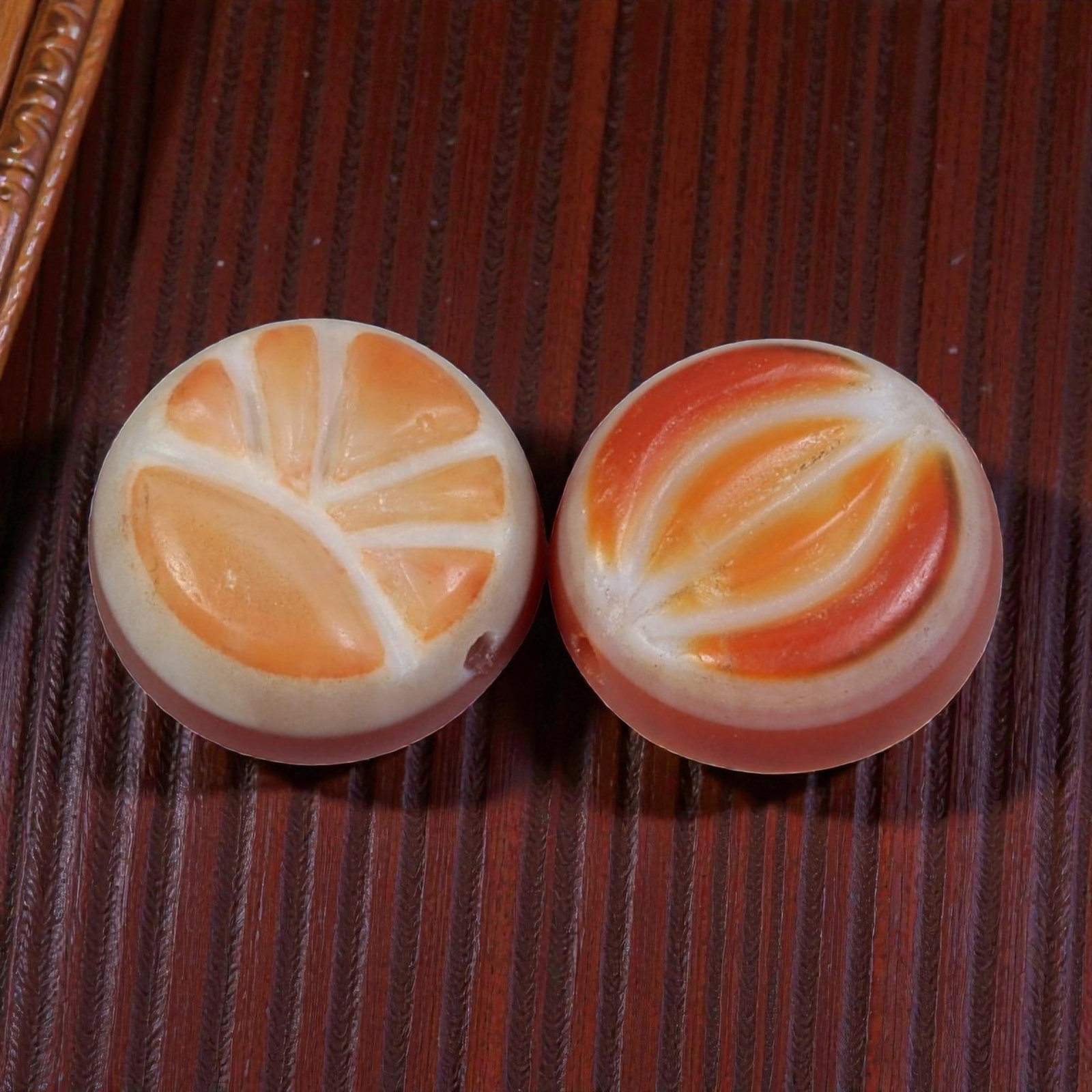 A Pair of Antique Himalayan Banded Carnelian Beads, 74AJ: The pair consists of two round, flat carnelian beads, each displaying distinct natural banding patterns. One bead features fan-like orange and white striations, while the other shows curved, eye-like 