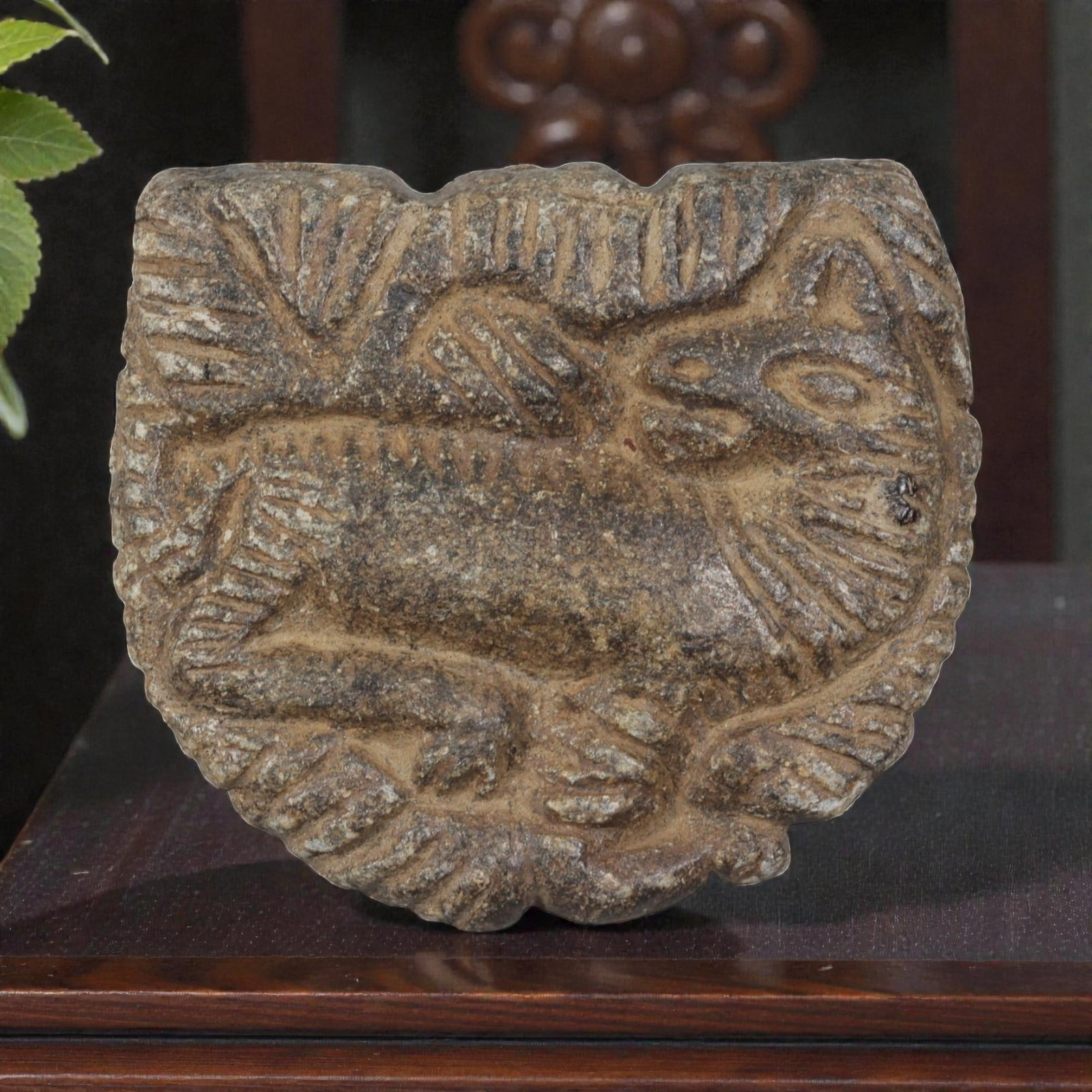 Ancient Near Eastern Schist Plaque with Recumbent Feline, Circa 1st Millennium BCE, 35AE: Carved from dark schist stone, this plaque features a recumbent feline, likely a lion or panther, in relief at the centre. The animal is depicted in profile, with incised lines defining its mane, faci