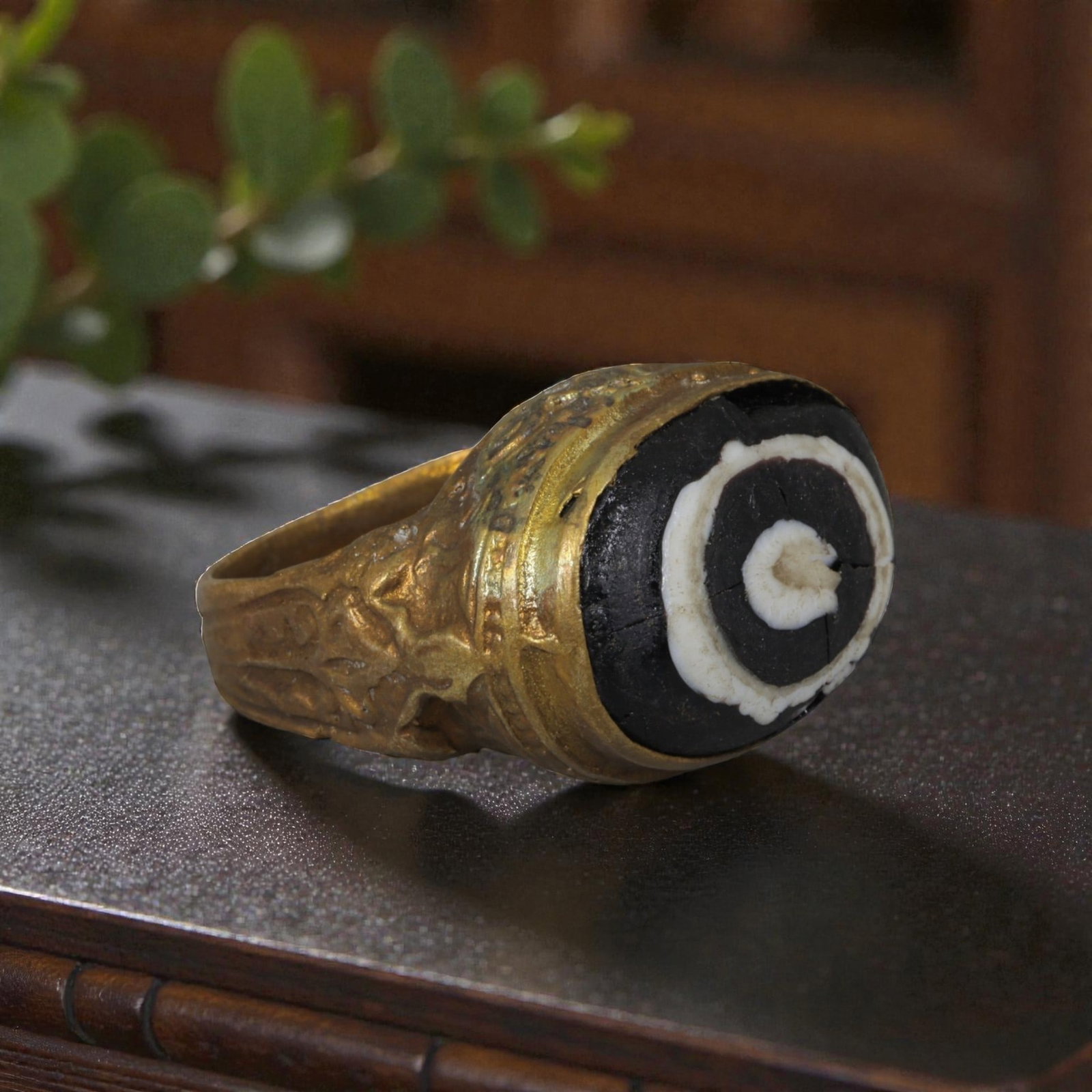 Antique Qajar Dynasty Gilt Evil Eye Ring, US Size 7.5, 17AJ: A gilt-metal ring of the Qajar period, US ring size 7.5, featuring an oval evil-eye glass inlay with a bold concentric black-and-white design (the glass exhibits age-related cracks). The bezel and wid