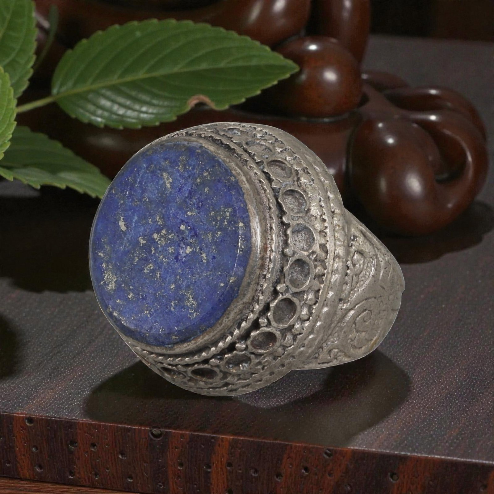 A Middle Eastern Silver Plated Lapis Lazuli Ring, Late 19th-Early 20th Century, 35AK: The ring is centered with a large round cabochon lapis lazuli stone exhibiting deep blue color with natural pyrite flecks, set within a wide domed bezel decorated with openwork circular patterns and t