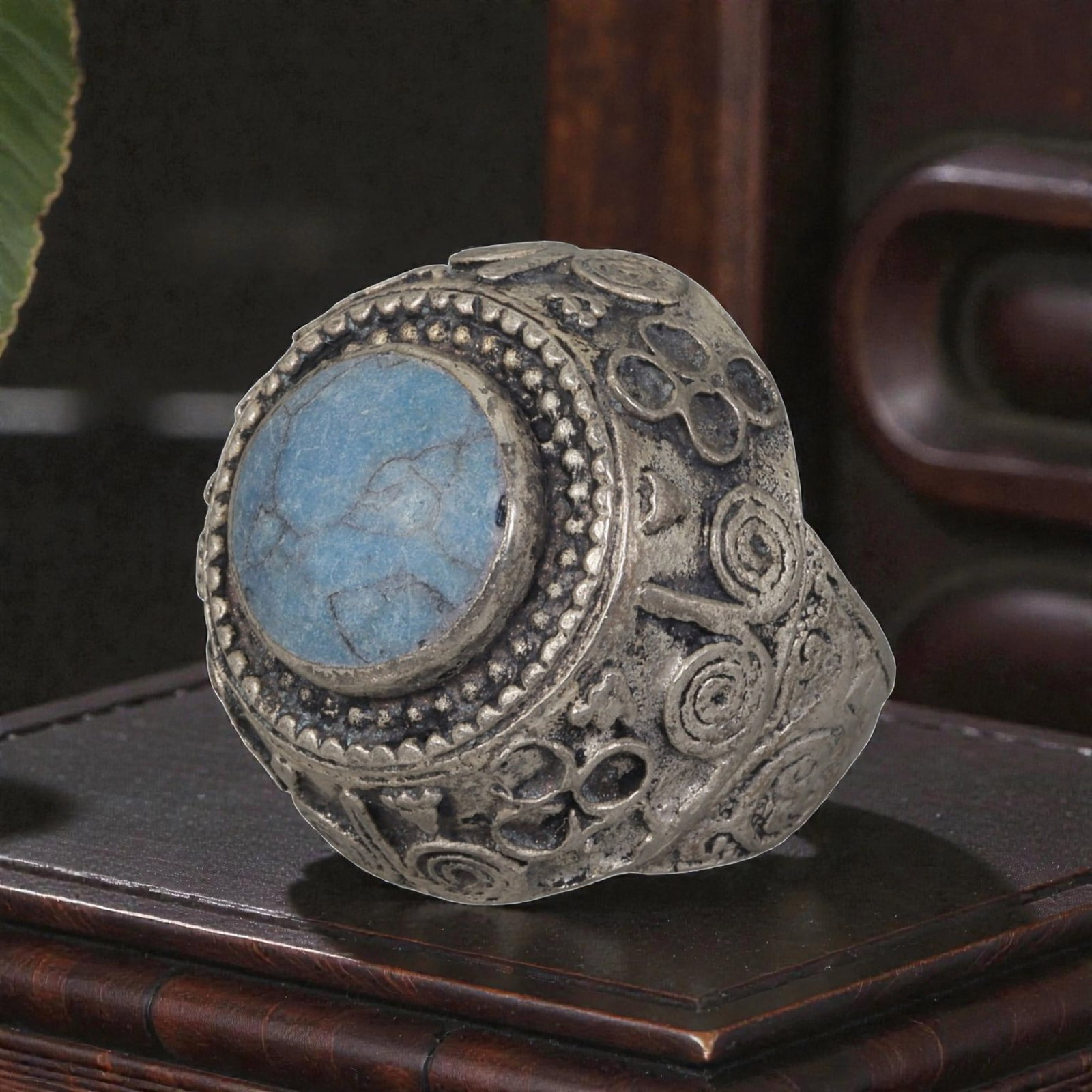 A Middle Eastern Silver Plated Turquoise Ring, Late 19th-Early 20th Century, 16AK: The ring is centered with a round cabochon turquoise stone exhibiting characteristic light blue color and natural surface veining, set within a domed bezel framed by beaded granulation. The bezel and 