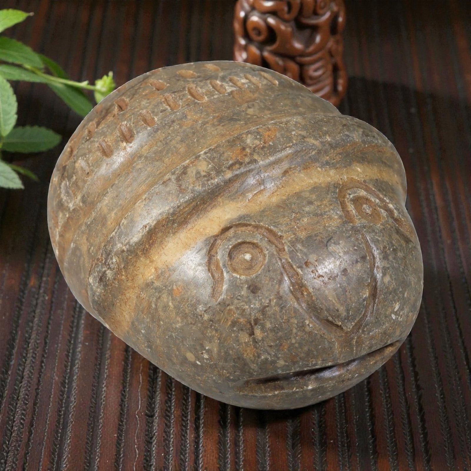 Ancient Silk Road Stone Weight, 47BA: A carved stone weight from the Silk Road region, of rounded form with incised decoration. The front features a stylized animal face, possibly representing a bird or owl, with defined eyes, beak, and m