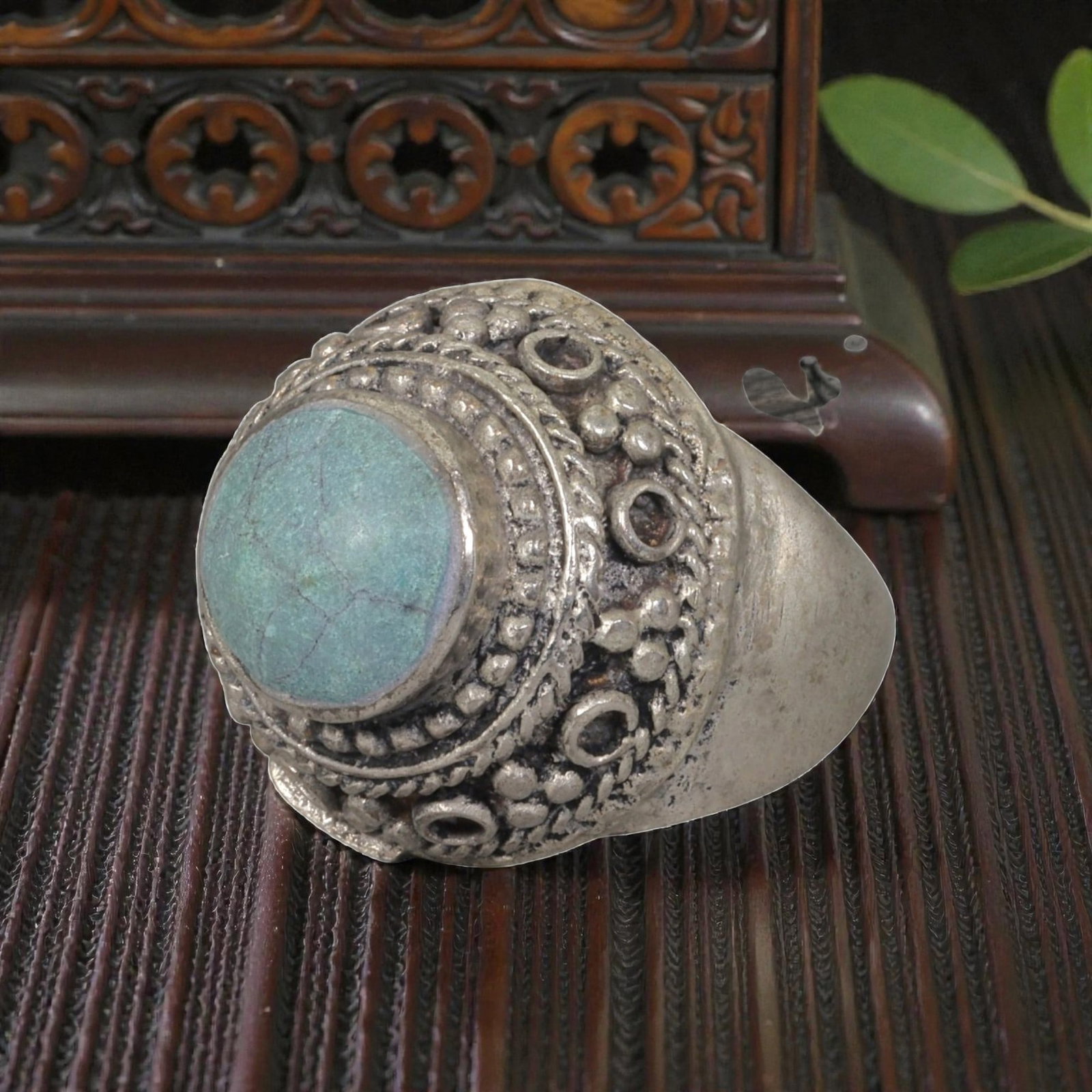 A Middle Eastern Silver Plated Turquoise Ring, Late 19th-Early 20th Century, 11AK: The ring is centered with a round cabochon turquoise stone exhibiting natural light blue-green tones and surface veining, set within a domed bezel decorated with beaded granulation, twisted wirework, 