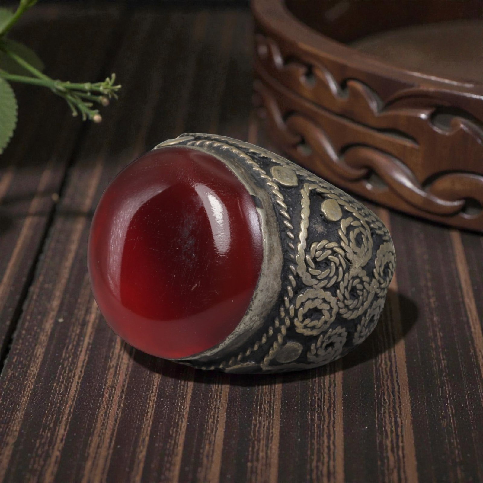 Antique Central Asian Silver and Carnelian Tribal Ring, 19th-Early 20th Century, 58AJ: The ring is set with a large, smooth cabochon carnelian stone. The silver mount is decorated with pseudo-filigree wirework and applied coiled motifs, set against a darkened background. The metal exhib