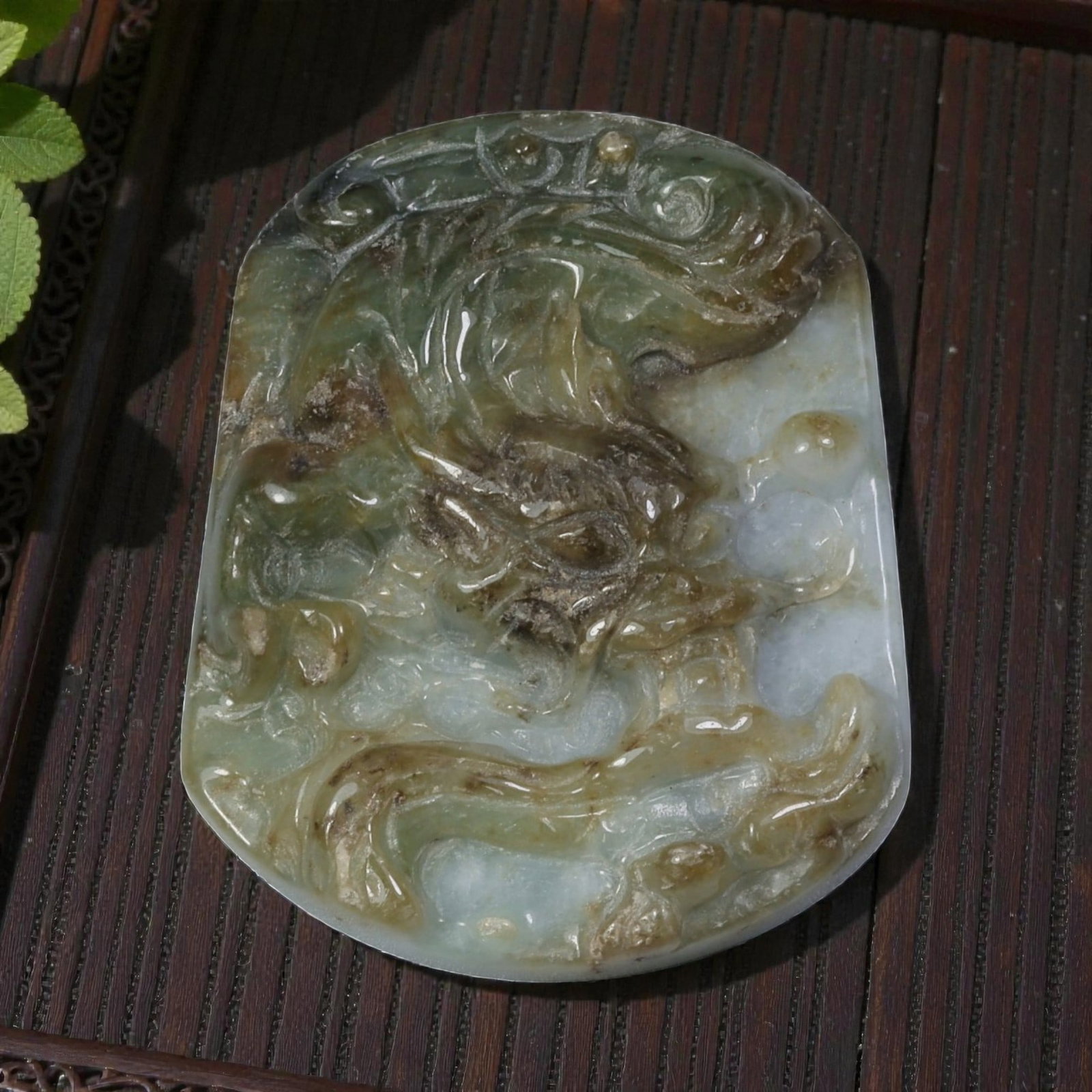 A Vintage Oriental Chinese Jadeite Jade Dragon Pendant, 38AG: Carved from multi-tonal jadeite with natural inclusions of green, brown, and pale lavender tones, the pendant is shaped as a shield plaque with rounded edges. The surface features a low-relief carving